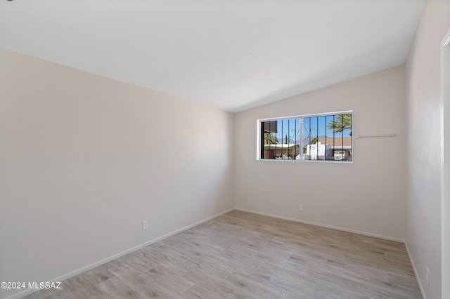 unfurnished room with light wood-type flooring and lofted ceiling