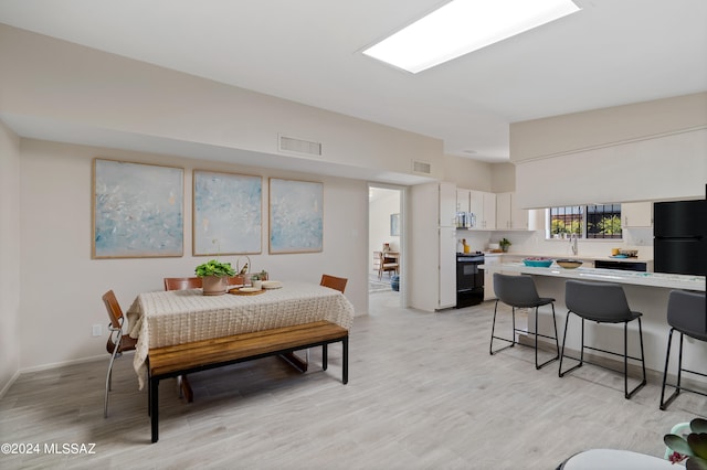 dining area with light wood-type flooring and sink