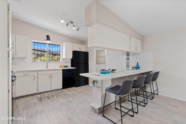 kitchen with sink, a kitchen breakfast bar, lofted ceiling, white cabinets, and black appliances