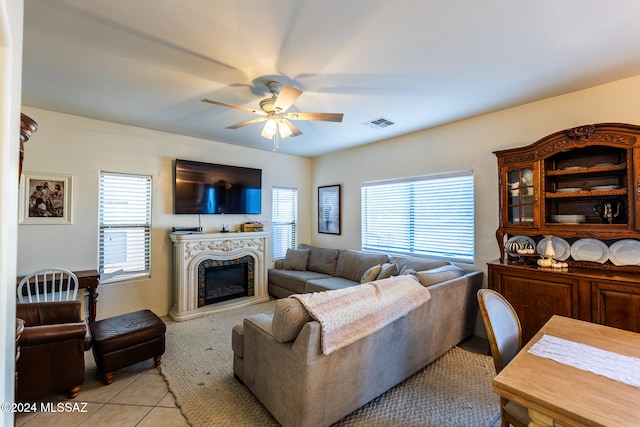 tiled living room with plenty of natural light, ceiling fan, and a premium fireplace