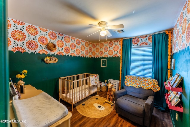 bedroom with ceiling fan, hardwood / wood-style floors, and a crib