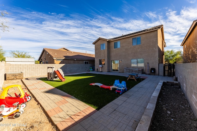 rear view of property featuring a lawn, a playground, and a patio