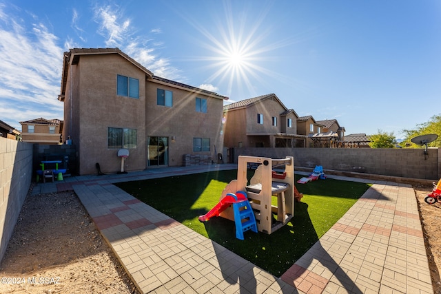 rear view of house with a lawn, a playground, and a patio