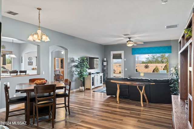 dining area featuring ceiling fan with notable chandelier, a healthy amount of sunlight, and dark hardwood / wood-style floors