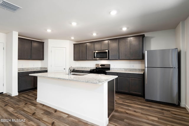 kitchen with sink, stainless steel appliances, dark hardwood / wood-style floors, dark brown cabinets, and a center island with sink