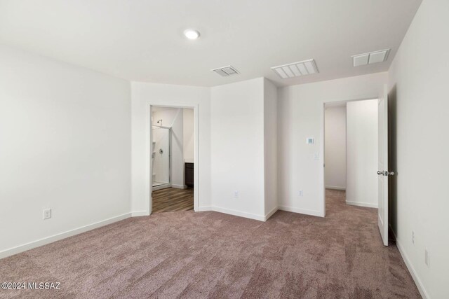 unfurnished bedroom featuring a spacious closet, light carpet, and a closet