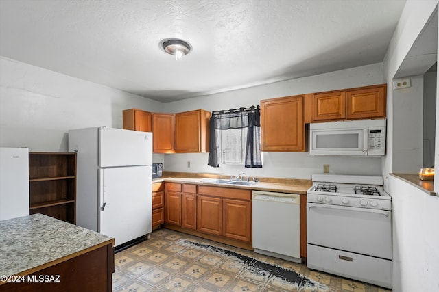 kitchen with a textured ceiling, white appliances, and sink