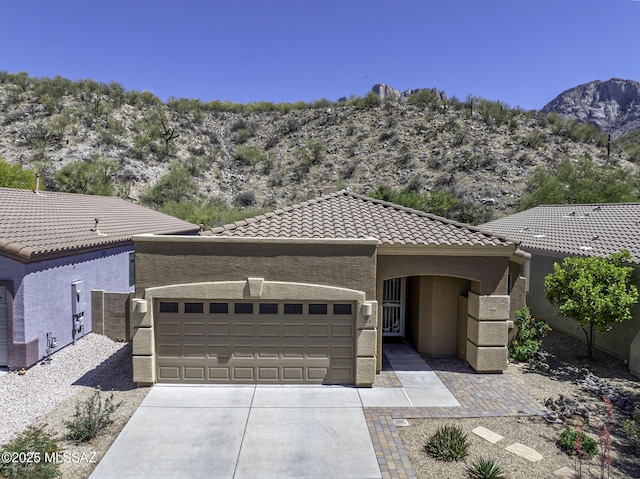 view of front of home featuring stucco siding, a tiled roof, an attached garage, a mountain view, and driveway