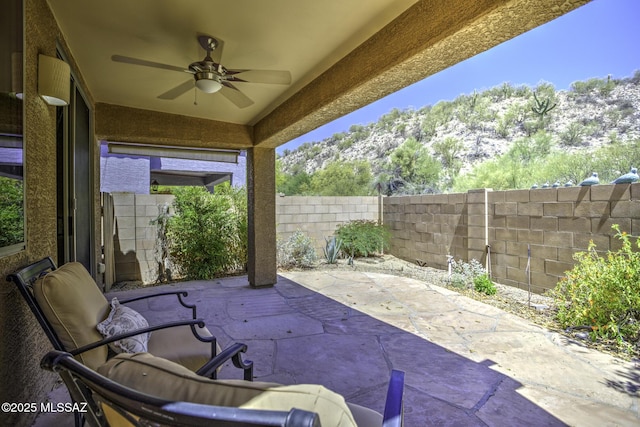 view of patio with ceiling fan, a mountain view, and a fenced backyard