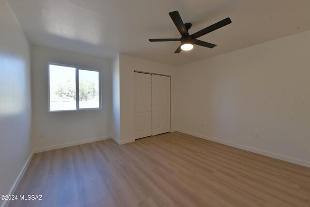 unfurnished bedroom featuring ceiling fan, light hardwood / wood-style floors, and a closet