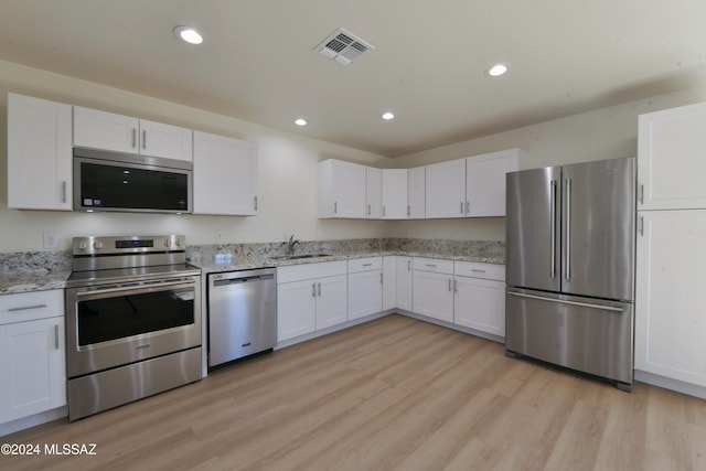 kitchen with light hardwood / wood-style flooring, white cabinets, and stainless steel appliances