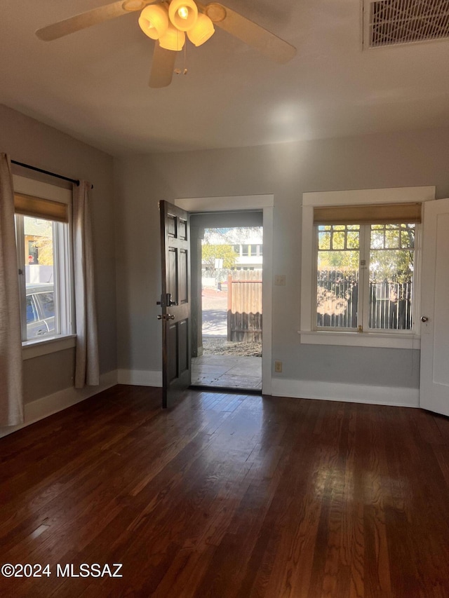 interior space featuring dark wood-style floors, baseboards, visible vents, and a ceiling fan