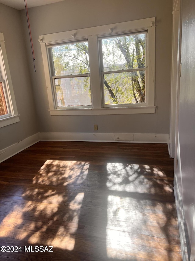 spare room with dark wood-style floors and baseboards