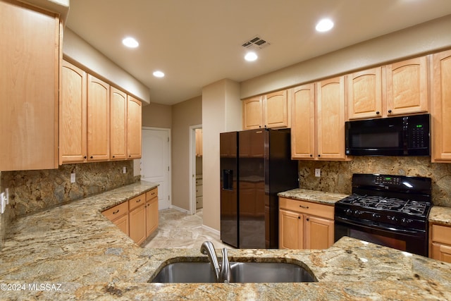 kitchen with light brown cabinetry, backsplash, light stone counters, sink, and black appliances