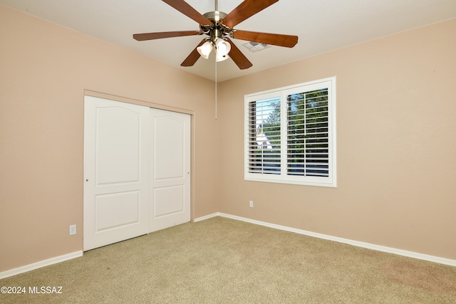 unfurnished bedroom with ceiling fan, light colored carpet, and a closet