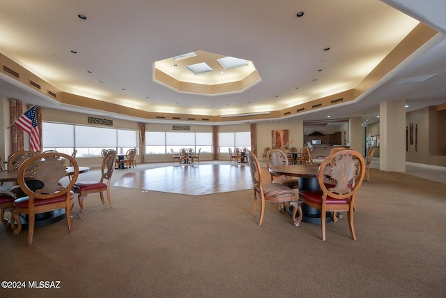 dining space featuring a healthy amount of sunlight, a raised ceiling, and carpet floors