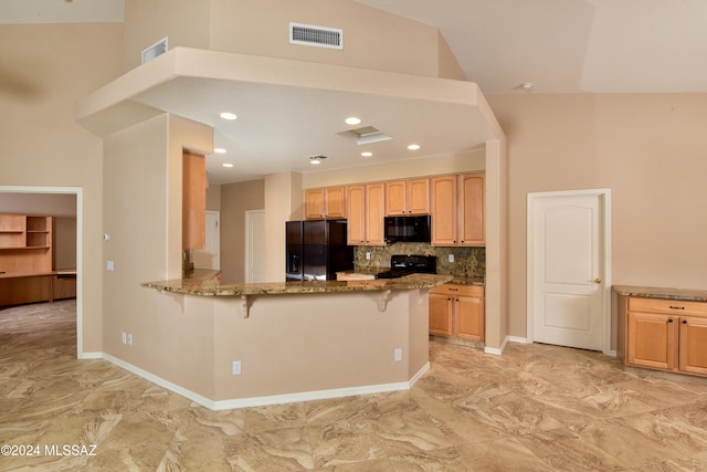 kitchen featuring a kitchen breakfast bar, backsplash, kitchen peninsula, stone countertops, and black appliances