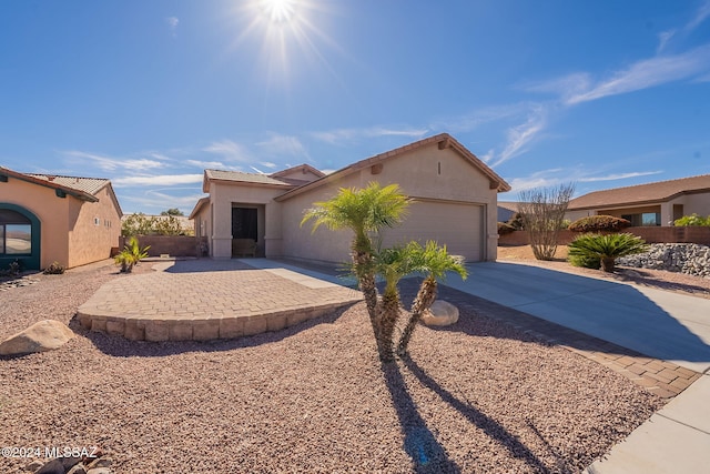 mediterranean / spanish-style home with an attached garage, fence, concrete driveway, stucco siding, and a patio area