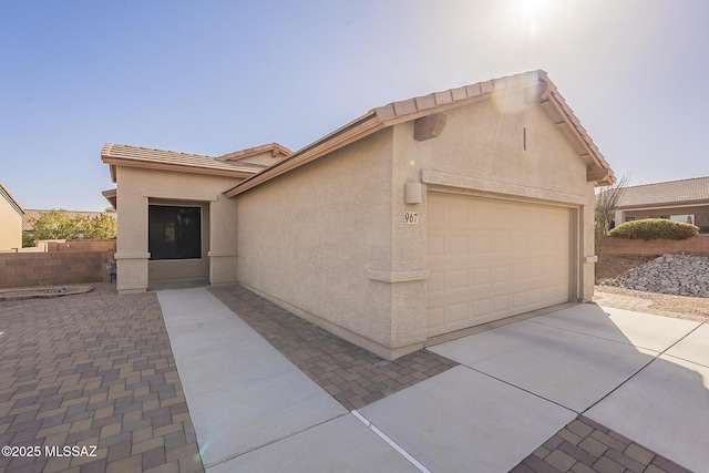 view of front of home with driveway, a tile roof, an attached garage, fence, and stucco siding