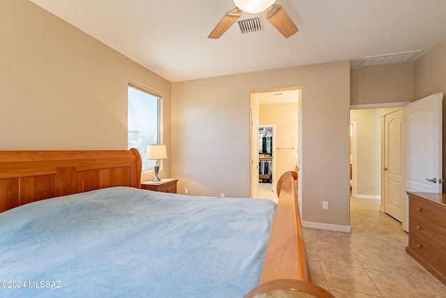 bedroom featuring light tile patterned floors, baseboards, visible vents, and a walk in closet