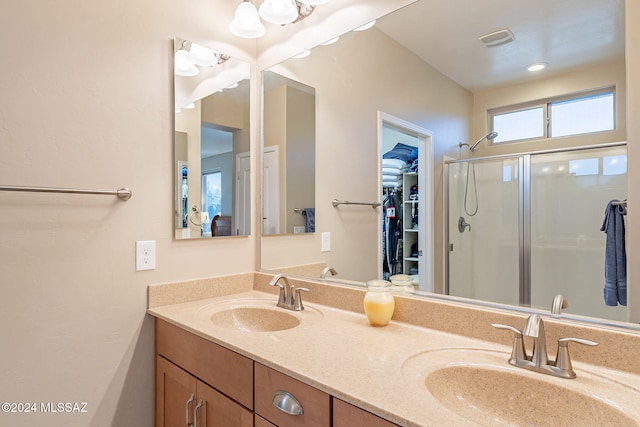 full bath featuring a stall shower, visible vents, a sink, and a spacious closet