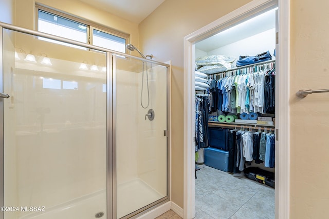 full bath featuring a stall shower, tile patterned flooring, and a walk in closet