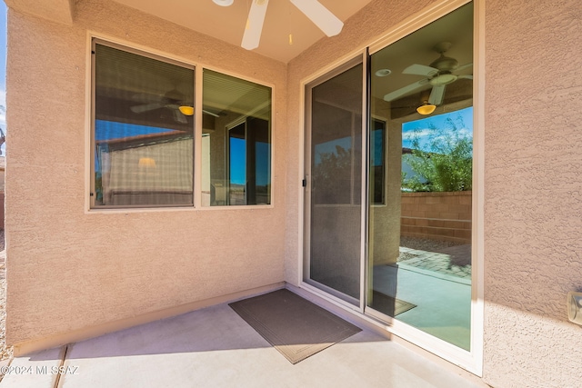 doorway to property featuring fence, a ceiling fan, and stucco siding