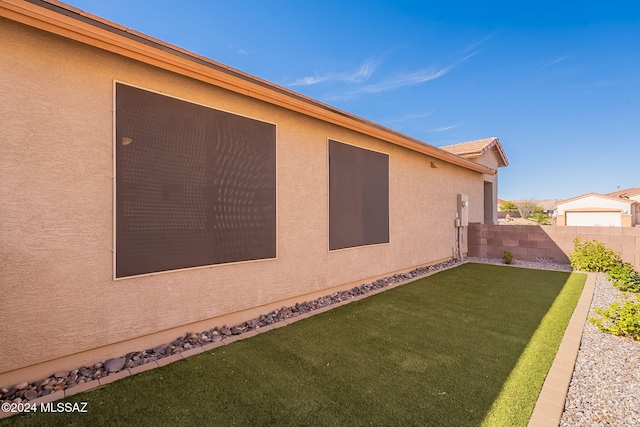 view of property exterior with a tiled roof, a lawn, fence, and stucco siding