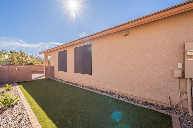 view of home's exterior with a yard, fence, and stucco siding