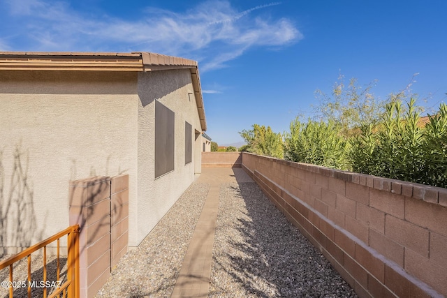 view of property exterior featuring a tile roof, a fenced backyard, and stucco siding