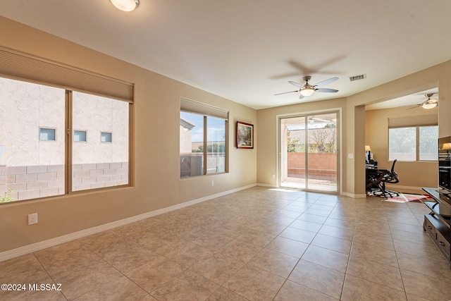 tiled spare room with a wealth of natural light, a ceiling fan, visible vents, and baseboards