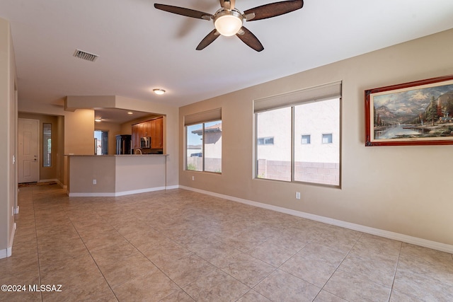 unfurnished living room with a ceiling fan, visible vents, baseboards, and light tile patterned flooring