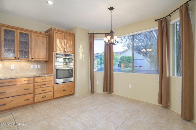 4594 S Moon River Pl, Green Valley, AZ 85622 - kitchen featuring double oven, brown cabinets, a chandelier, backsplash, and light tile patterned flooring