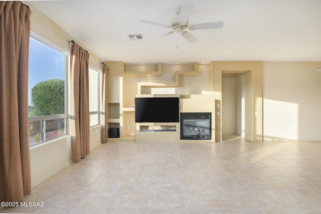 4594 S Moon River Pl, Green Valley, AZ 85622 - unfurnished living room with light tile patterned floors, ceiling fan, a glass covered fireplace, and healthy amount of natural light