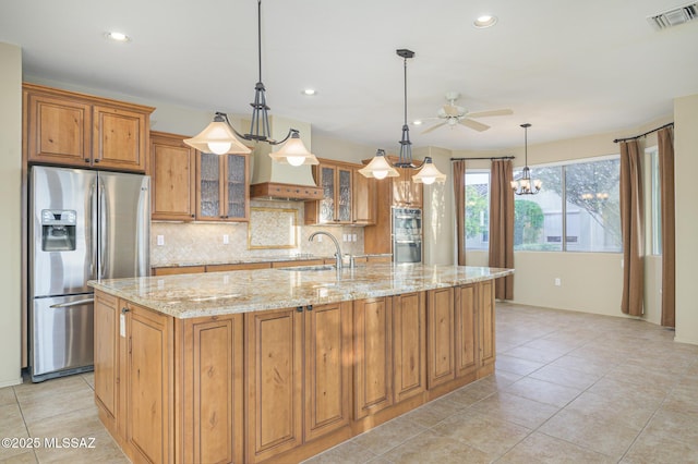 4594 S Moon River Pl, Green Valley, AZ 85622 - kitchen with stainless steel appliances, ceiling fan, a kitchen island with sink, light stone counters, and brown cabinets