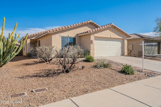 view of front of property with a garage, a tile roof, driveway, and stucco siding