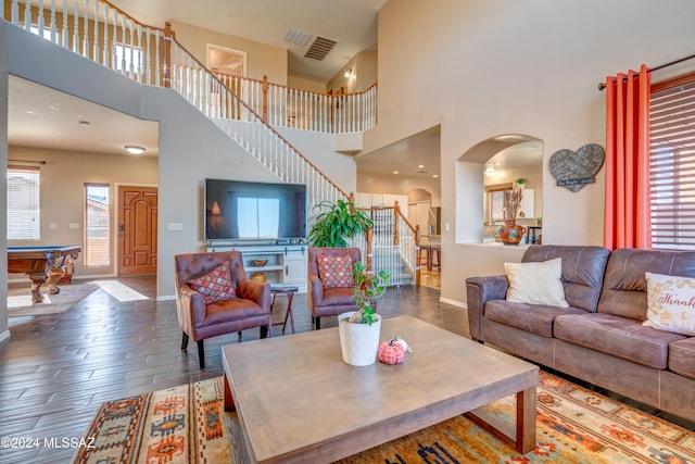 living room with arched walkways, visible vents, wood finished floors, baseboards, and stairs