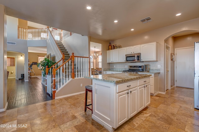 kitchen featuring baseboards, visible vents, appliances with stainless steel finishes, and light stone counters