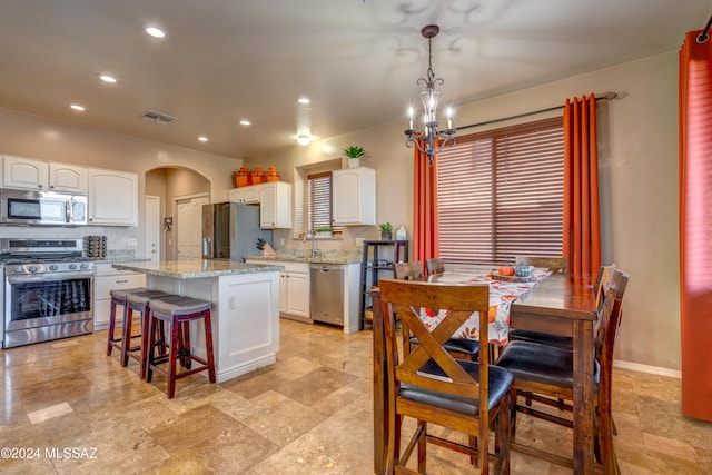 kitchen with visible vents, arched walkways, a kitchen island, appliances with stainless steel finishes, and white cabinetry