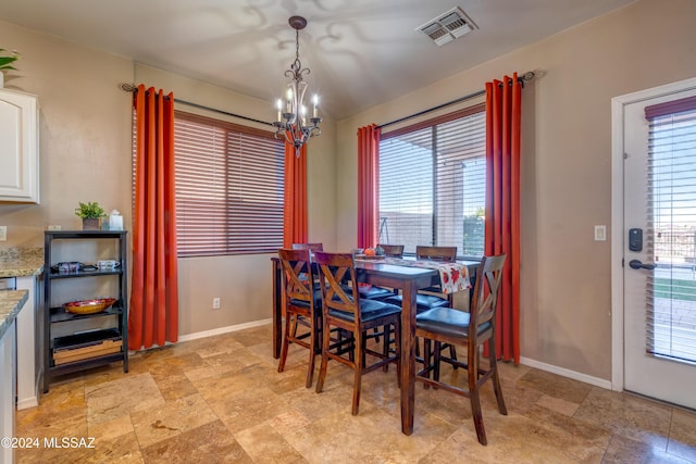 dining area featuring stone finish floor, visible vents, baseboards, and an inviting chandelier