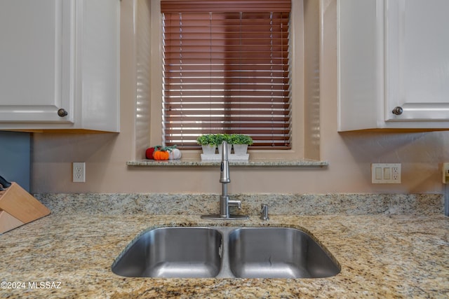 interior details with light stone counters, white cabinetry, and a sink