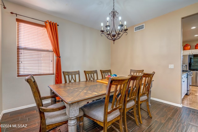 dining area featuring an inviting chandelier, baseboards, visible vents, and wood finished floors