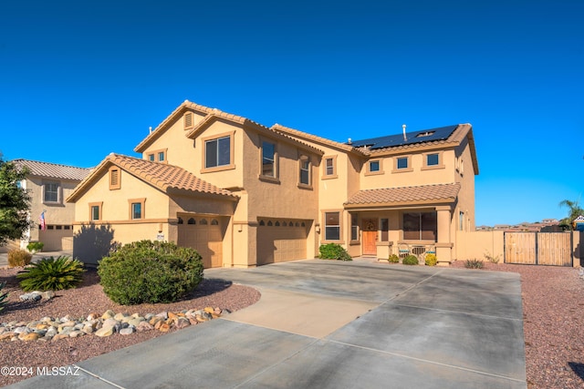 mediterranean / spanish home featuring a porch, a garage, a gate, roof mounted solar panels, and stucco siding