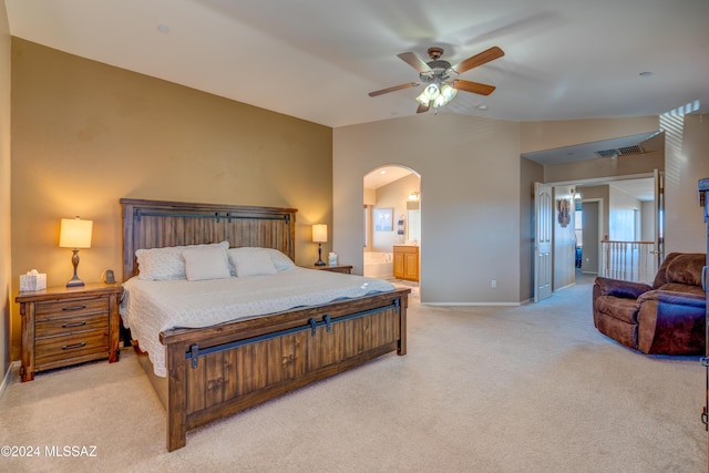 bedroom with visible vents, arched walkways, light colored carpet, lofted ceiling, and ensuite bath