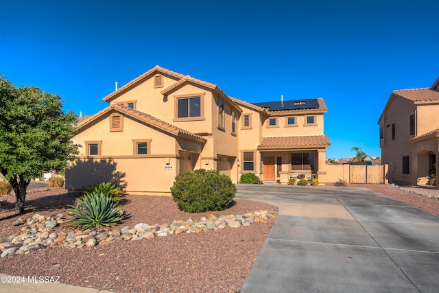 mediterranean / spanish-style house with stucco siding, fence, a tiled roof, and solar panels