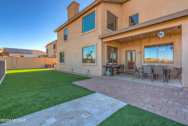 rear view of property with a patio, a fenced backyard, a tiled roof, a lawn, and stucco siding