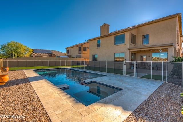 view of pool with a patio area, fence, and a pool with connected hot tub