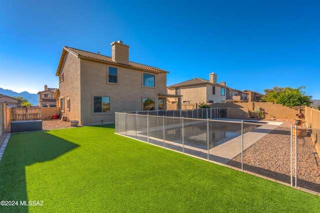 rear view of house with a fenced backyard, a tile roof, a lawn, stucco siding, and a chimney