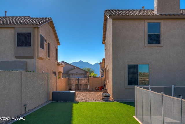 view of yard with a fenced backyard, central AC unit, and a mountain view