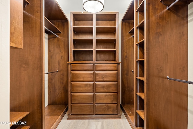 walk in closet with light hardwood / wood-style floors